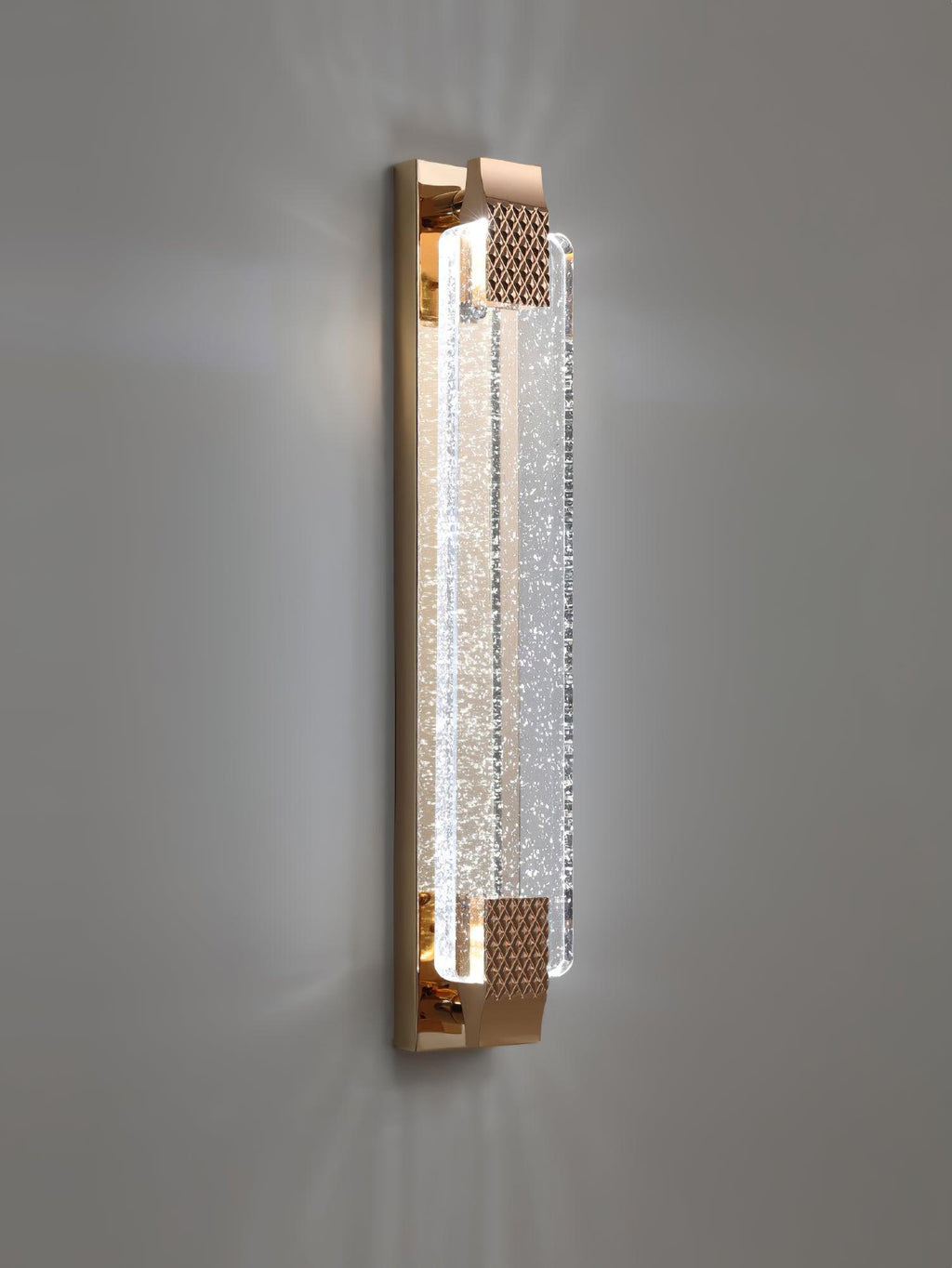 Vertical Clérachic bubble-crystal wall light lit on a grey wall, light spreading up and down from the gold ends.