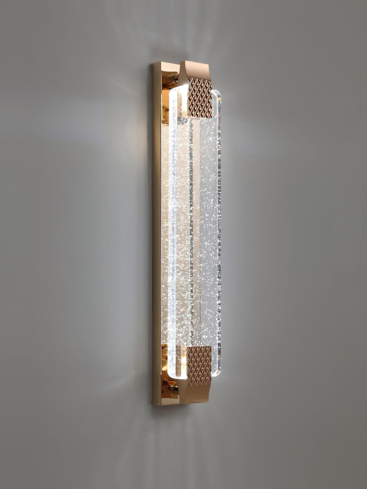 Vertical Clérachic bubble-crystal wall light lit on a grey wall, light spreading up and down from the gold ends.
