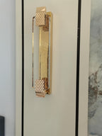 Close view of the diamond-pattern end caps and clear crystal bar on this Clérachic wall light, mounted beside a marble panel.