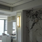 Customer-style photo of this Clérachic wall light glowing in a niche beside a veined marble wall in a modern apartment.
