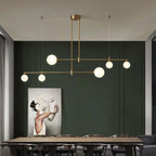 The Clérachic 6-head bubble-glass bar pendant spans a dining table set below a green panelled wall and a framed floral artwork.