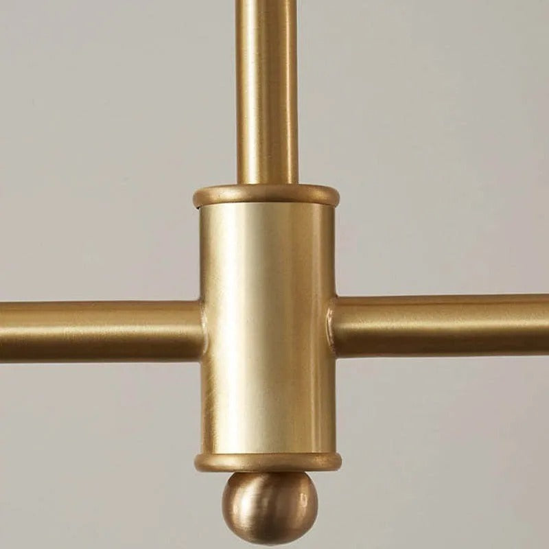 Close-up of the Clérachic pendant's central hub, where the two staggered brass-tone bars cross above a small ball finial.