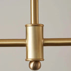 Close-up of the Clérachic pendant's central hub, where the two staggered brass-tone bars cross above a small ball finial.
