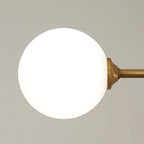 Close-up of a single opal glass globe on the Clérachic bubble-glass bar pendant's brass-tone arm.