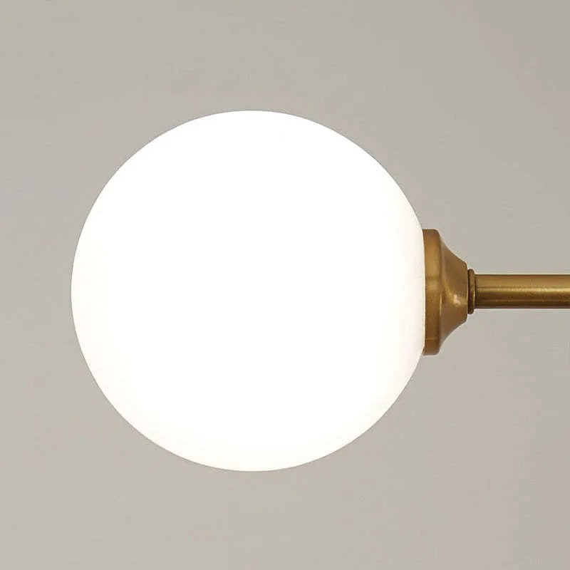 Close-up of a single opal glass globe on the Clérachic bubble-glass bar pendant's brass-tone arm.