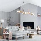 Gold Clérachic bubble glass pendant light hanging above a gray sofa and fireplace in a vaulted living room.