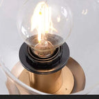 Close-up of the filament bulb inside a clear glass globe on the gold Clérachic bubble glass pendant.