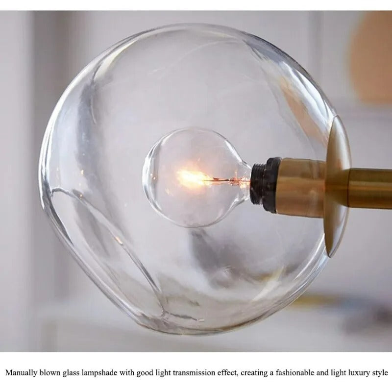 Close-up of a single clear glass globe and its filament bulb on the gold Clérachic bubble glass pendant.