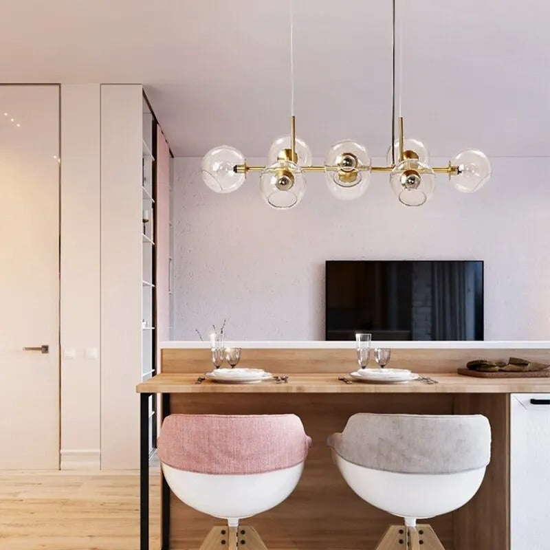 Gold Clérachic bubble glass linear pendant light above a breakfast bar with cushioned stools and place settings.