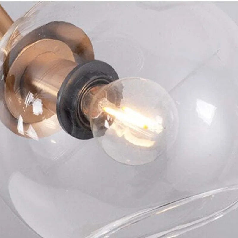 Extreme close-up of the socket hardware and filament bulb inside a clear globe on the gold Clérachic pendant.