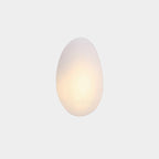 Clérachic Bubble Glass Wall Sconce in white, the tall egg Model A lit low so a soft warm core spreads through the frosted glass.