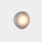Smoky gray Clérachic Bubble Glass Wall Sconce, the squat round Model D, lit with a broad warm centre for a hallway or landing.