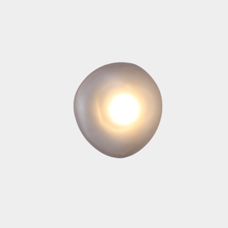 Smoky gray Clérachic Bubble Glass Wall Sconce, the squat round Model D, lit with a broad warm centre for a hallway or landing.