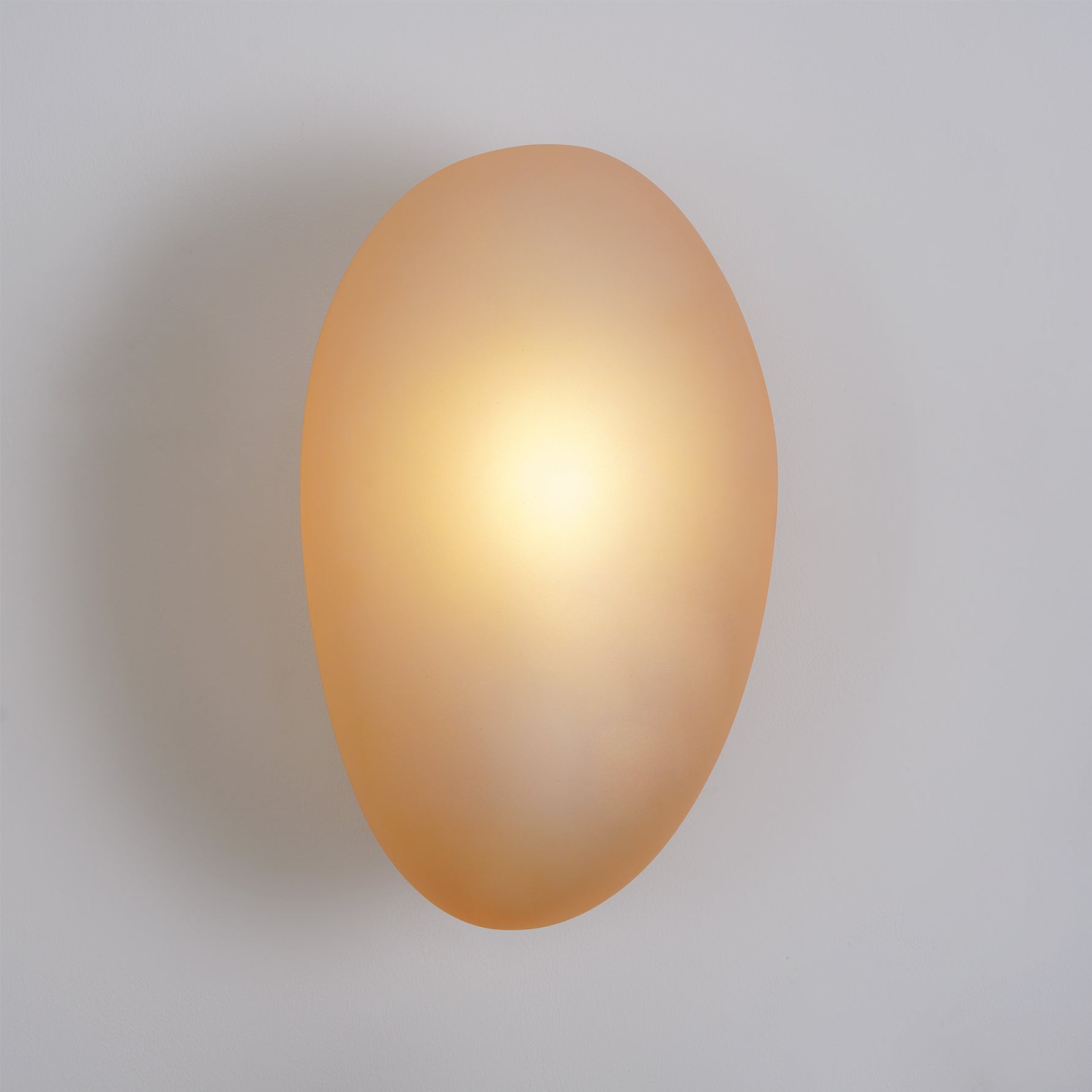 Clérachic Bubble Glass Wall Sconce in amber mounted flush to a plain painted wall, casting a soft shadow with no visible arm or stem.