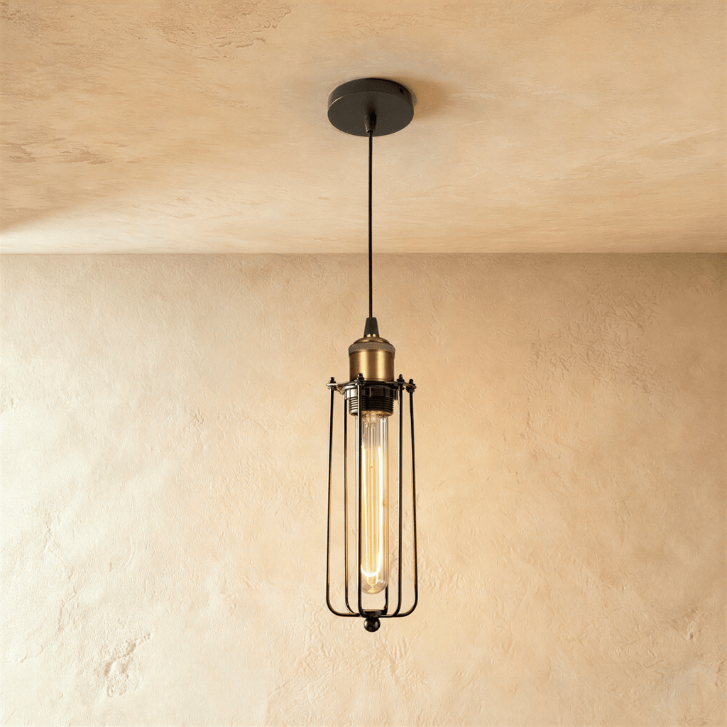 Clérachic slim black wire-cage pendant with a brass socket and a long amber filament bulb, hung from a black canopy.