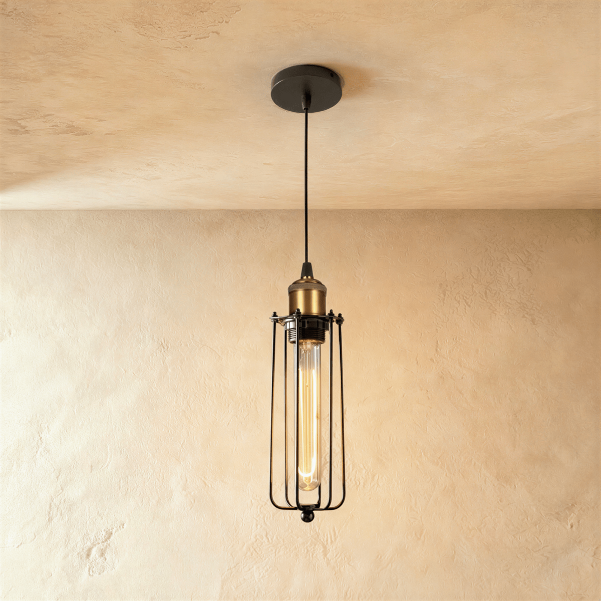 Clérachic slim black wire-cage pendant with a brass socket and a long amber filament bulb, hung from a black canopy.