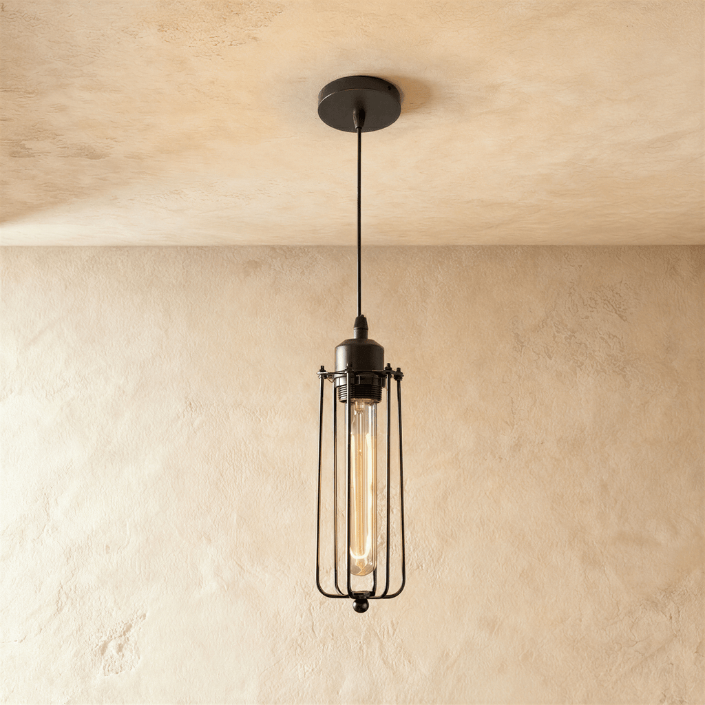 Clérachic slim all-black wire-cage pendant with a long filament bulb glowing amber, on a black cord and canopy.