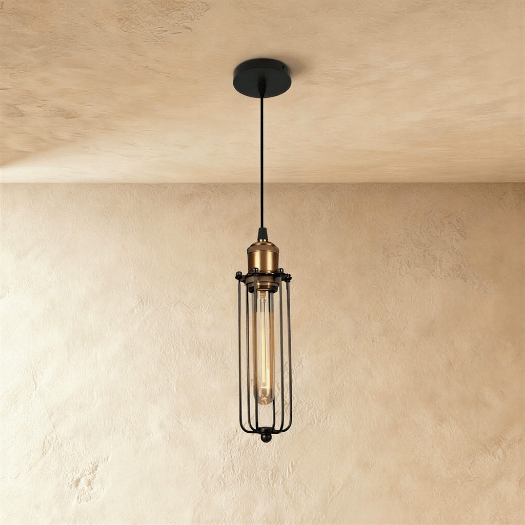 Clérachic narrow black cage pendant with a brass socket and a tube filament bulb, hanging against a limewashed wall.