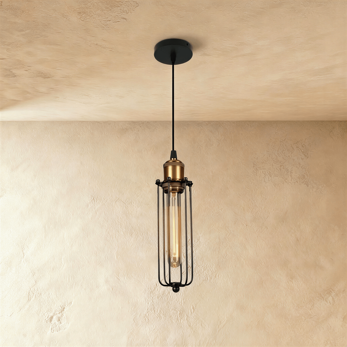 Clérachic narrow black cage pendant with a brass socket and a tube filament bulb, hanging against a limewashed wall.