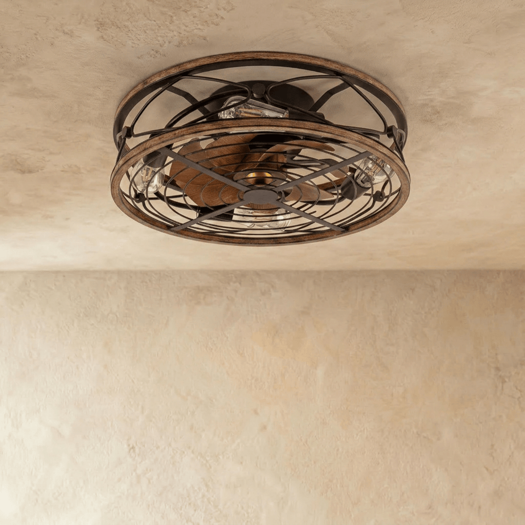 Clérachic caged ceiling fan with light viewed from below, wood-look blades behind a dark metal cage and unlit filament bulbs.