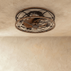Clérachic caged ceiling fan with light viewed from below, wood-look blades behind a dark metal cage and unlit filament bulbs.