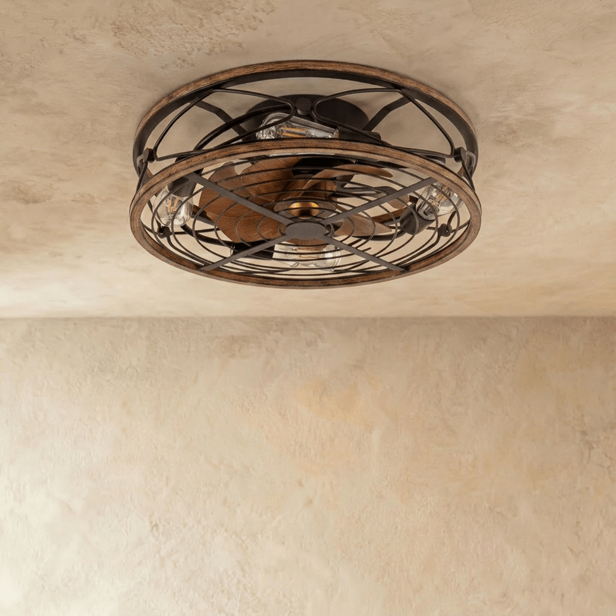 Clérachic caged ceiling fan with light viewed from below, wood-look blades behind a dark metal cage and unlit filament bulbs.