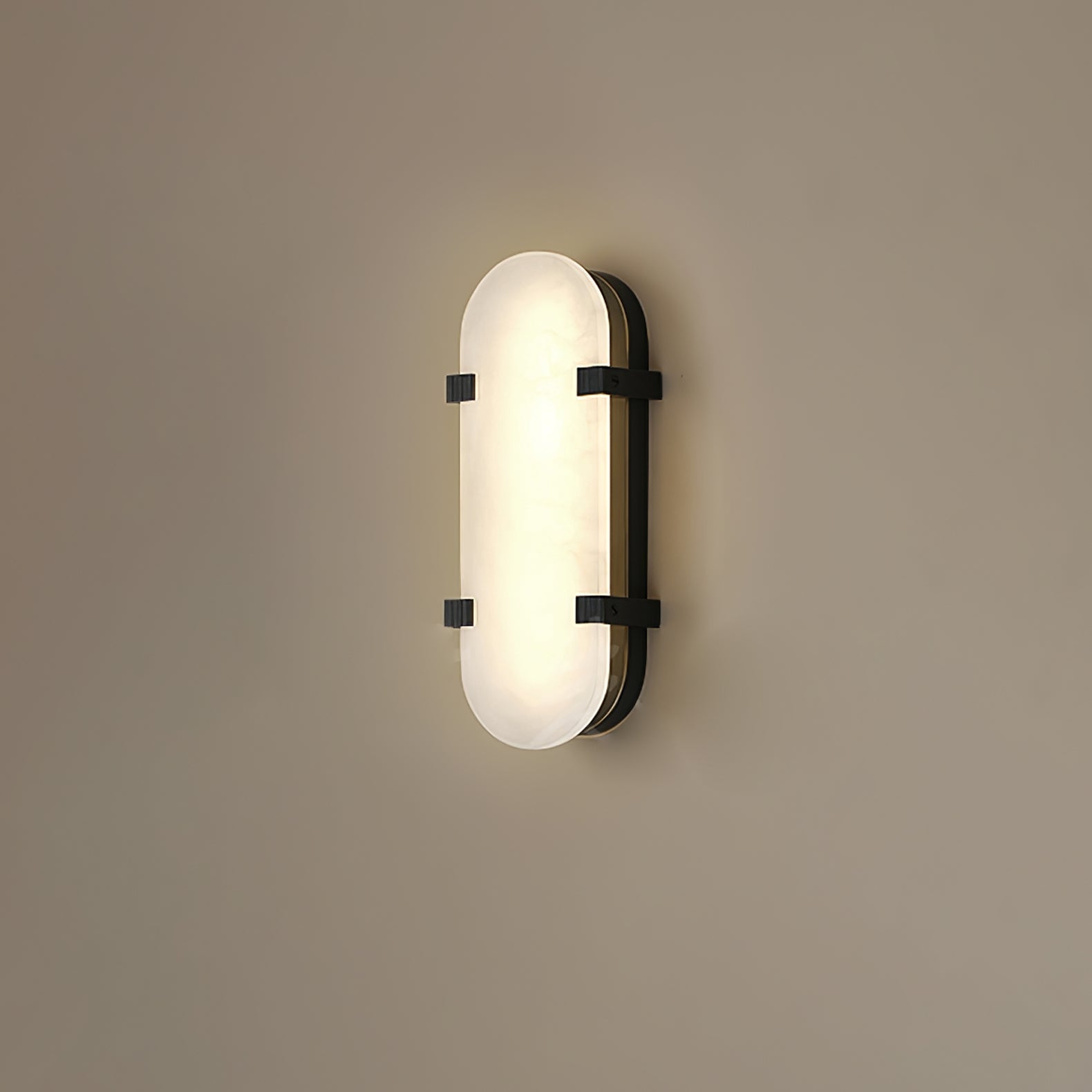 The Clérachic Calla wall light in black finish, its oval stone face glowing softly.