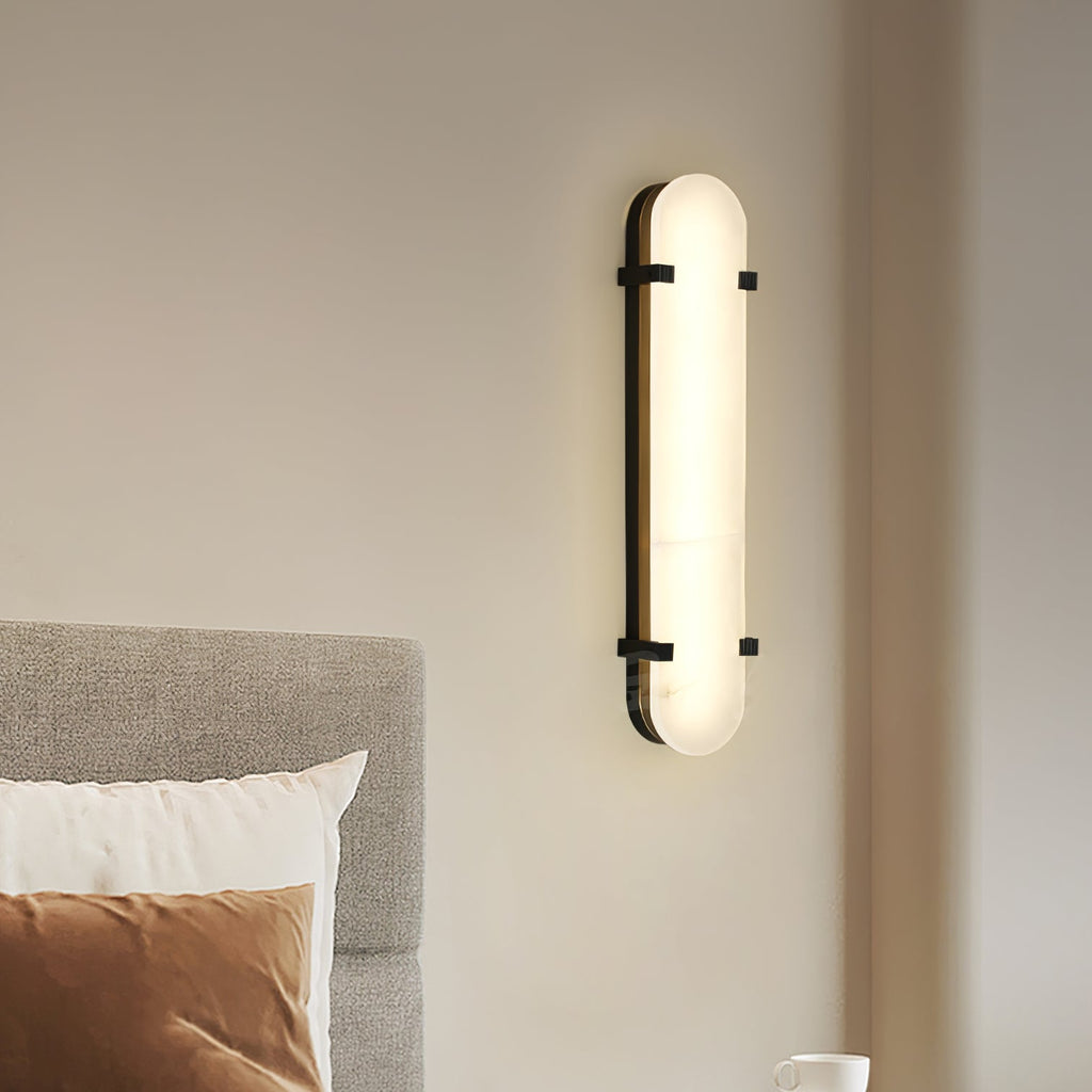 Clérachic Calla wall light beside a grey upholstered headboard and rust velvet cushion.