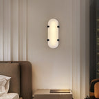 Clérachic Calla wall light lit above a sofa in a panelled room with tall windows.