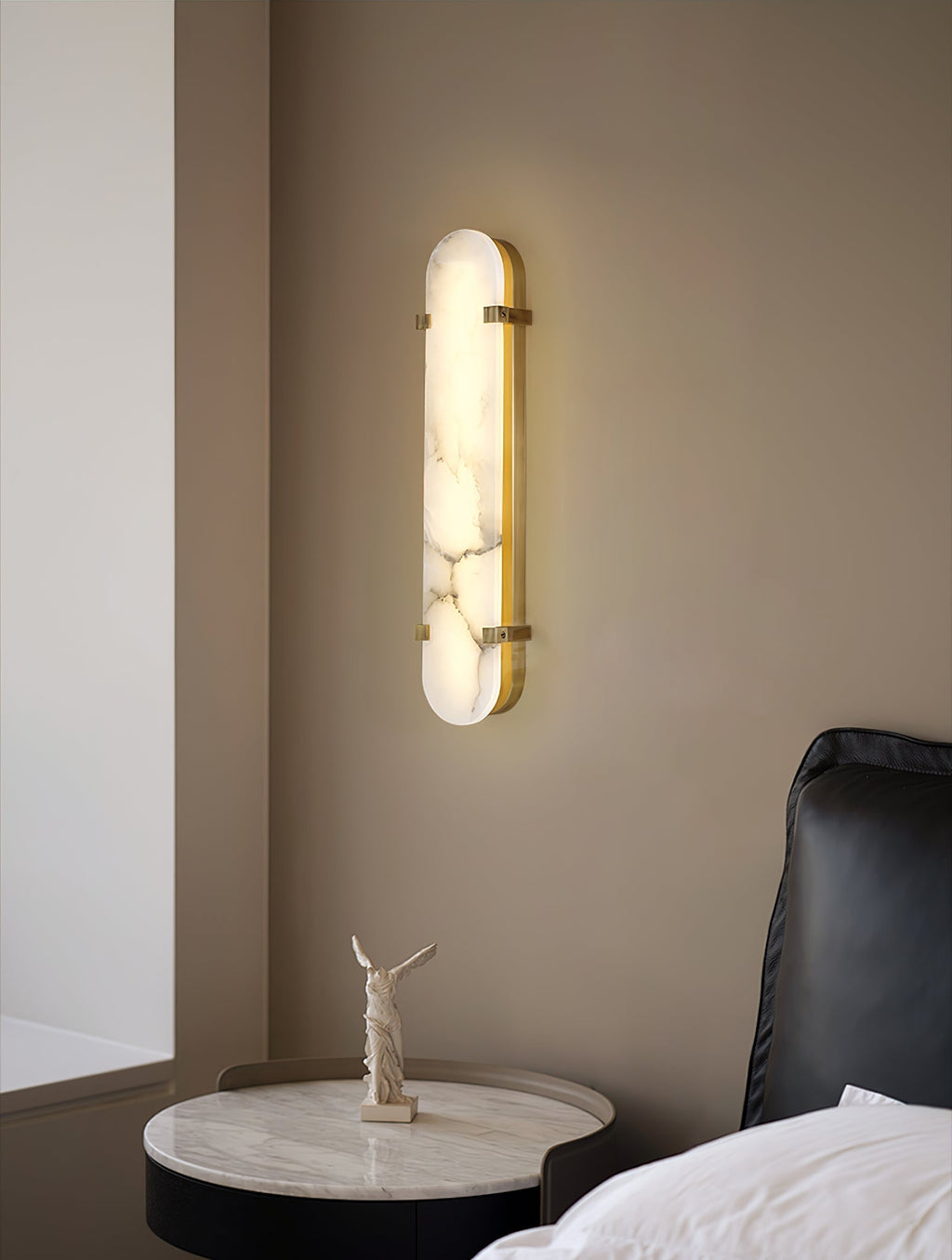 The Clérachic Calla wall light above a black armchair and round marble side table.