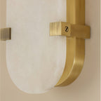 Macro of the Clérachic Calla bracket, ribbed brass strap clamped over the alabaster face.