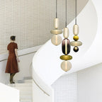Clérachic pendants hung at staggered heights over a spiral staircase, their olive and smoked glass stacks lit from within.