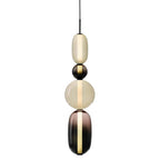 Clérachic pendant on a white background, an opal capsule, black ball, opal globe and smoked capsule on one black cord.