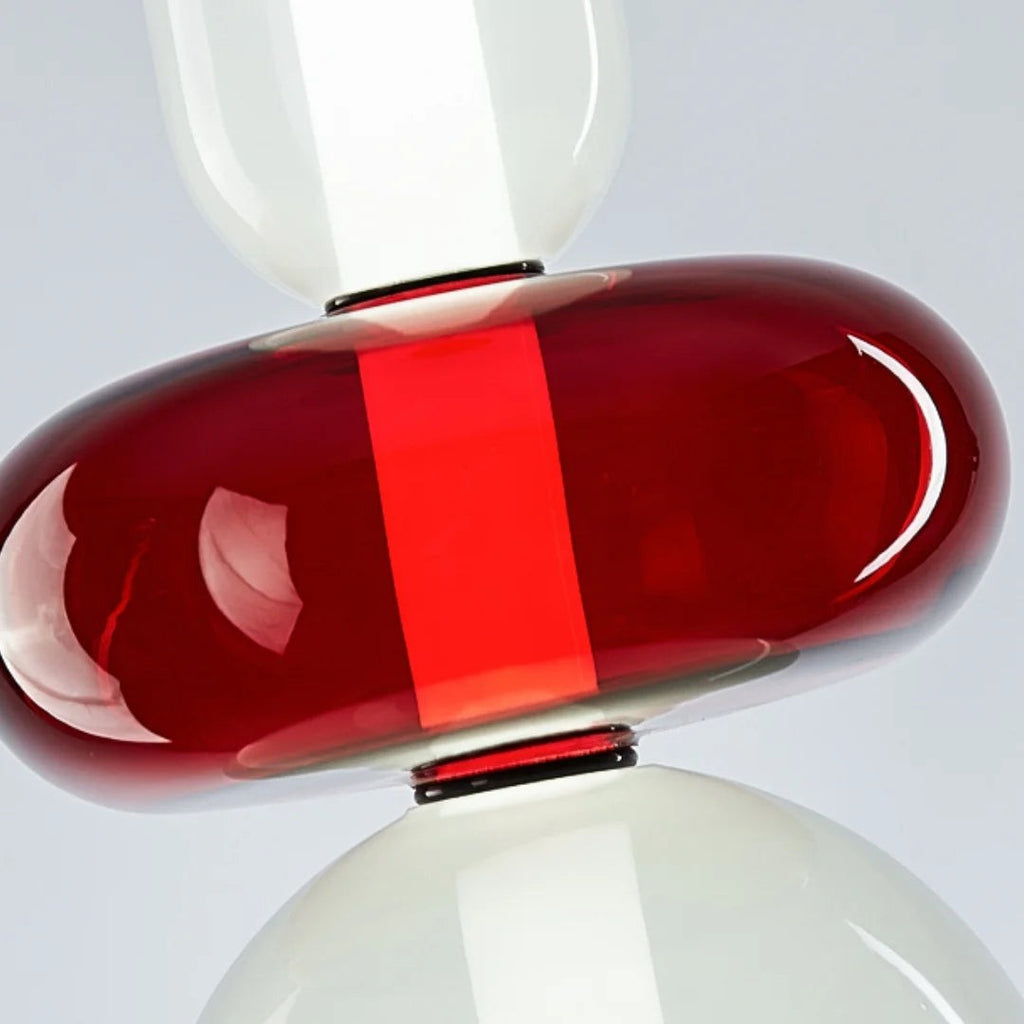 Close view of the red glass disc on this Clérachic pendant, with the vertical LED glowing through the hand-blown glass.