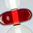 Close view of the red glass disc on this Clérachic pendant, with the vertical LED glowing through the hand-blown glass.