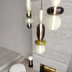 Looking down on a cluster of Clérachic pendants at different heights in a tall stone-walled room with a fireplace below.