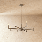 Clérachic eight-arm chandelier in champagne gold with filament bulbs on straight bars, centred on a limewash wall.