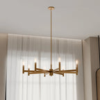 Clérachic eight-arm gold chandelier with candle-style bulbs hung low in front of sheer white curtains and a window.