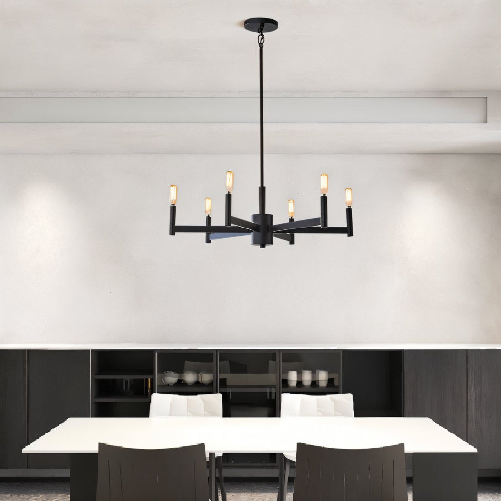 Clérachic six-arm black chandelier over a white dining table with dark chairs, in front of a low black sideboard.