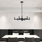 Clérachic six-arm black chandelier over a white dining table with dark chairs, in front of a low black sideboard.
