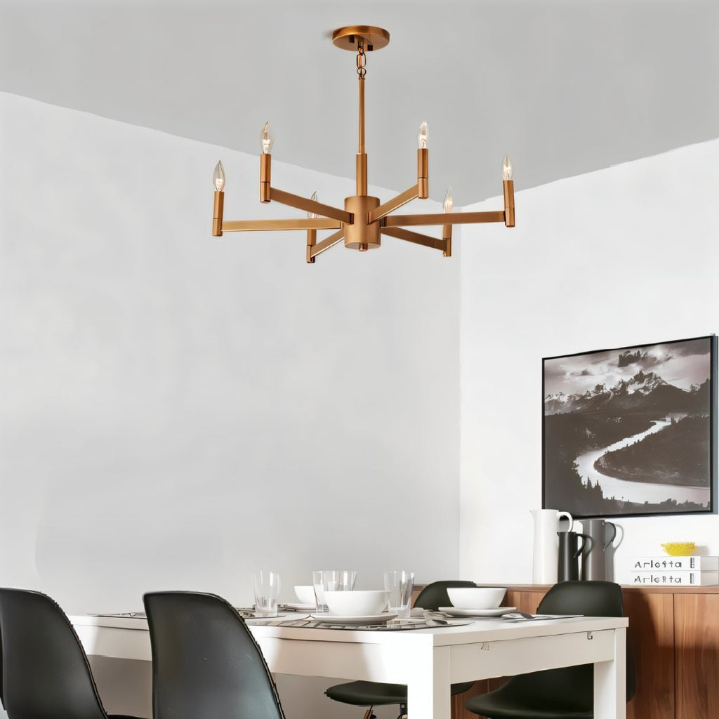 Clérachic six-arm brass chandelier with candle bulbs over a white dining table and black chairs in a bright room.