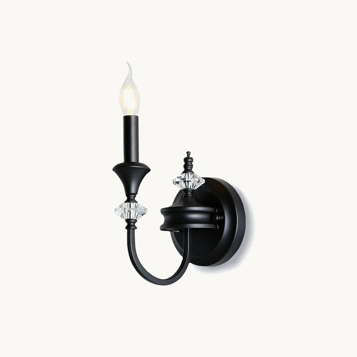 Single-arm Clérachic wall light in black on a plain white backdrop, a candle-style bulb above crystal accents on a curved iron arm.