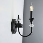 Side view of a black single-arm Clérachic wall light on a grey wall, its curved iron arm reaching out from a round backplate.