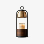 Candle warmer lamp from Clérachic with a brushed gold dome, black frame and walnut base, a jar candle sitting under the dome.