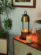 Clérachic candle warmer lamp on a wooden chest with the candle jar set beside it, its walnut base glowing under the dome.