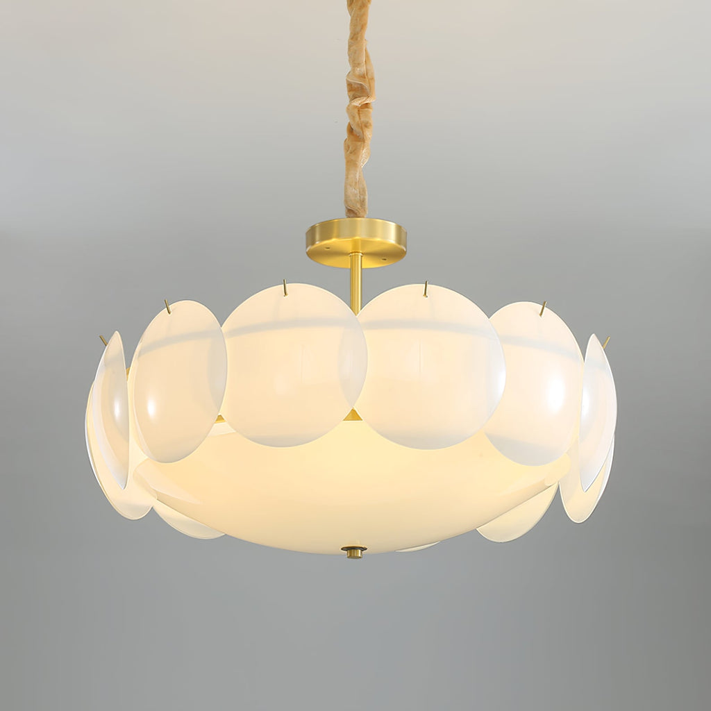 Brass canopy and stem above the ring of round, frosted white shades on this Clérachic chandelier, seen against a soft grey backdrop.