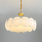Brass canopy and stem above the ring of round, frosted white shades on this Clérachic chandelier, seen against a soft grey backdrop.