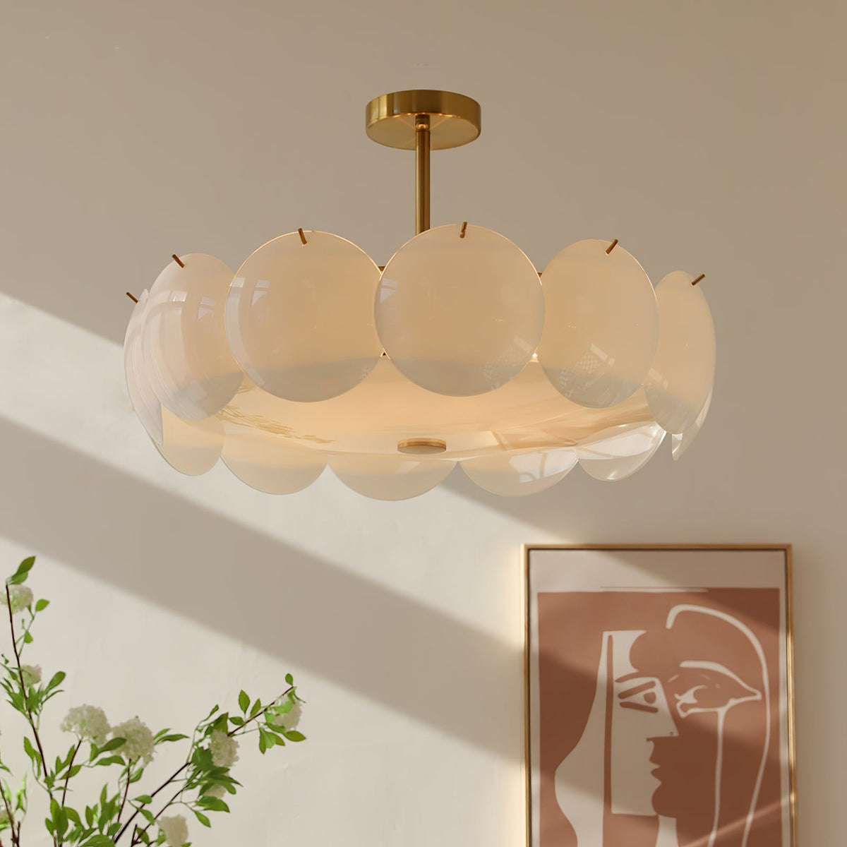 Semi-flush version of this Clérachic chandelier, its overlapping pale shades catching sunlight beside a framed abstract print and a leafy branch.