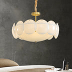 This Clérachic chandelier glowing softly on its chain against a dark charcoal wall, with the edge of a pale sofa below.