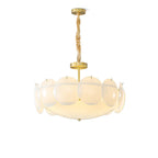 Clérachic chandelier in a front view on white, brass canopy, twisted chain and a ring of frosted shell shades lit from within.